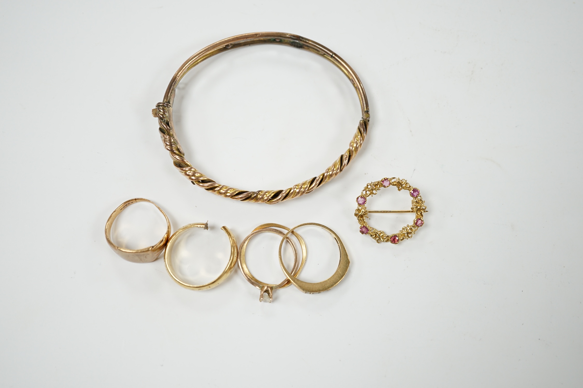 An early 20th century 9ct hinged bangle, three assorted 9ct gold rings and a modern 9ct gold and gem set brooch and two other yellow metal rings, gross weight 23.2 grams. Condition - poor